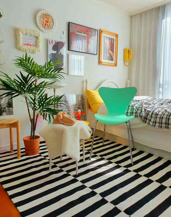 White-toned bedroom featuring checkered bedding and a modern green chair with a cozy atmosphere