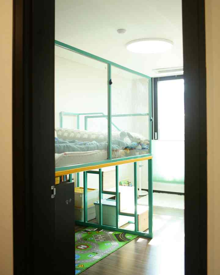 白と緑のトーンの子供部屋、特注の二段ベッドと子供用プレイマットが配置された明るく実用的な空間