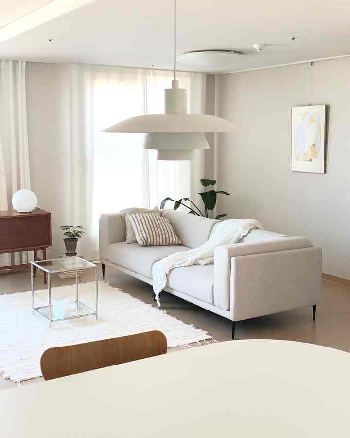 ホワイトとベージュの色調のリビング、ファブリックソファとペンダントライトが配置されたナチュラルでモダンなインテリア