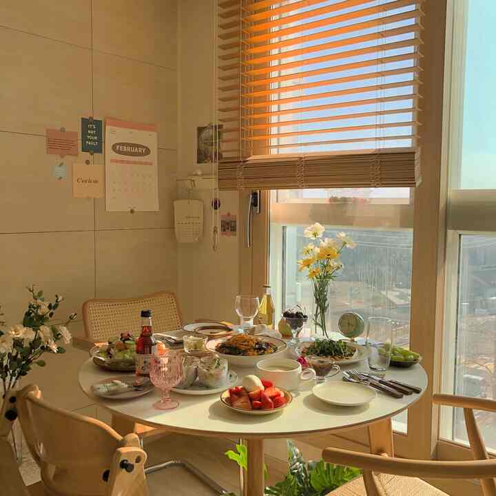 暖かいナチュラルトーンのリビングダイニング、円形テーブルとアームチェアが配置されたホームパーティースペース