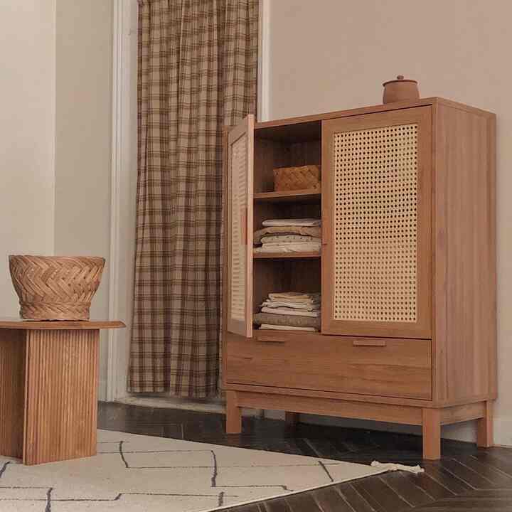 ナチュラルな木目調のキッチン収納キャビネットとチェックのカーテン、シンプルなラグが配置された温かみのある印象的な空間