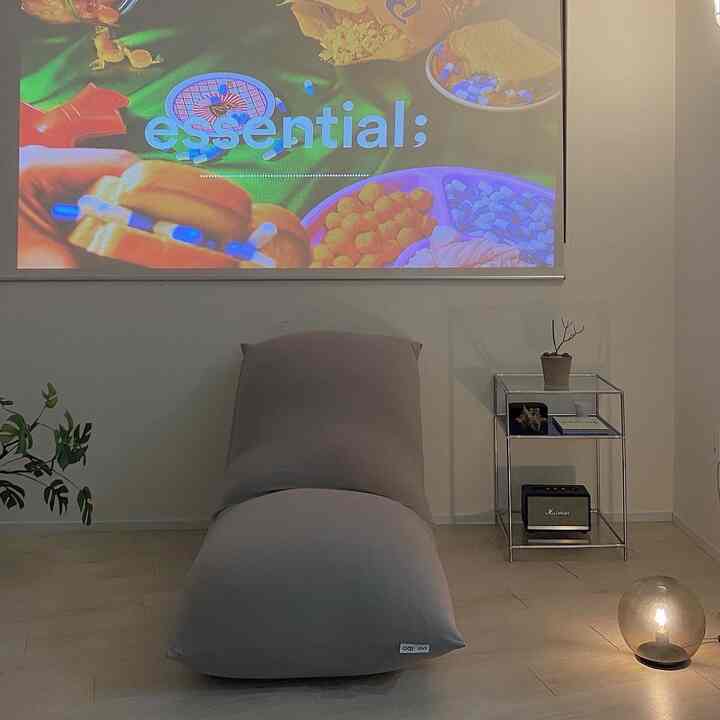 Gray-toned living room featuring a central bean bag sofa, simple metal side table, and ambient lighting in a minimal modern interior