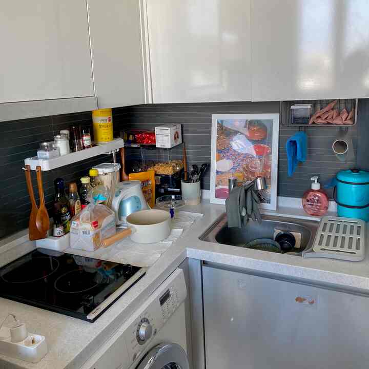 白とグレーのトーンのコンパクトなキッチン、整理された棚とトレイが配置された清潔でモダンなインテリア