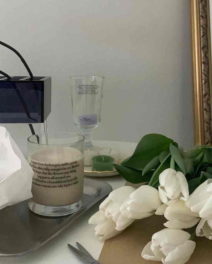 White and beige toned living room interior featuring white tulips and candles on a table, creating a natural atmosphere