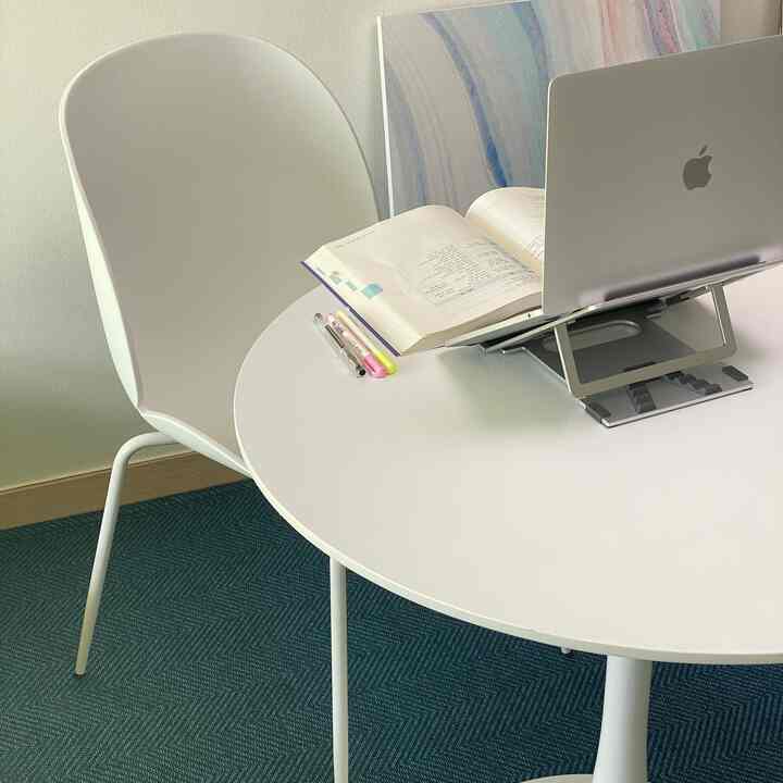 ホワイトとネイビートーンのワンルームのホームオフィス、円形テーブルとチェアが配置された清潔な勉強と作業空間