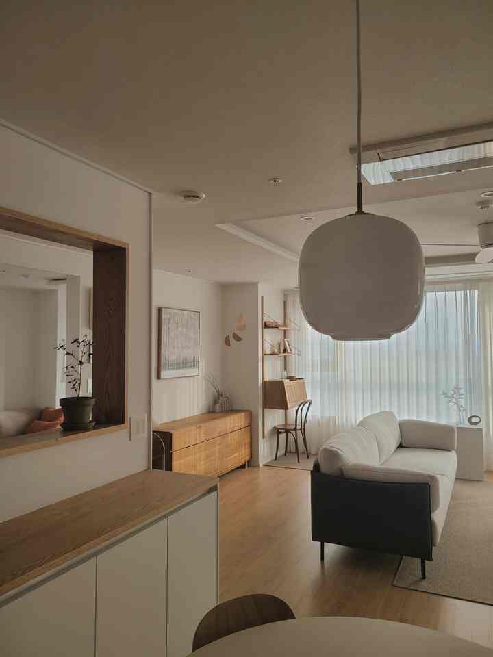 Natural wood tones and white walls in a natural modern living room and kitchen seamlessly connected with a sofa