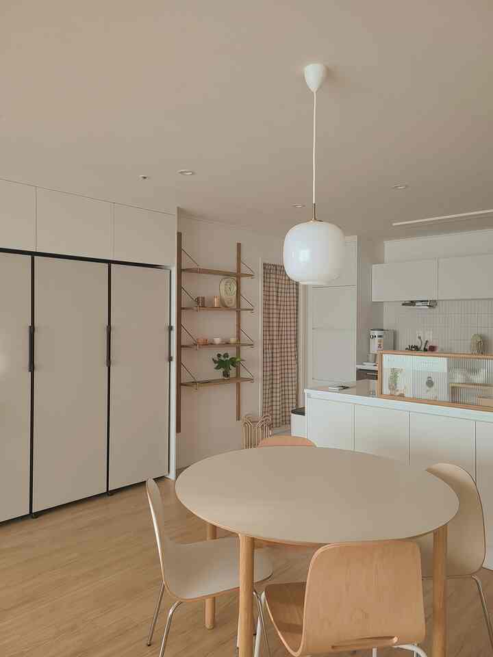 ホワイトとウッドトーンのキッチン・ダイニング空間、丸いダイニングテーブルとペンダントライトが配置された雰囲気のあるナチュラルモダンなインテリア