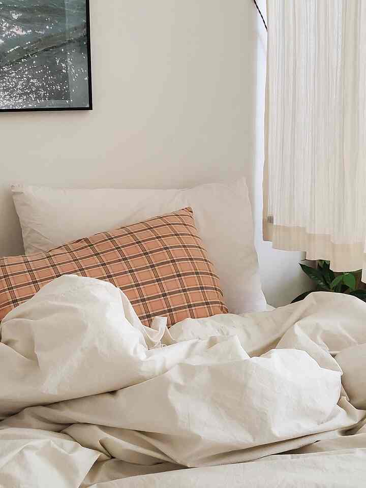 Beige bedroom space featuring apricot check pillow covers and cream-colored duvet cover with a cozy atmosphere