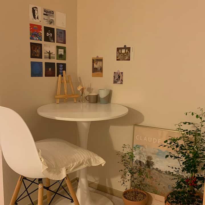 ベージュの壁と白い丸テーブルがあるナチュラルな雰囲気の一人暮らし向けの小さなリビング空間