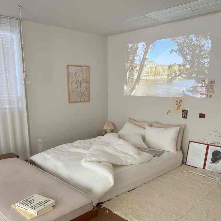 柔らかなホワイトとベージュの色調の寝室、ロータイプのベッドと白い寝具が配置されたナチュラルで落ち着いた雰囲気のインテリア