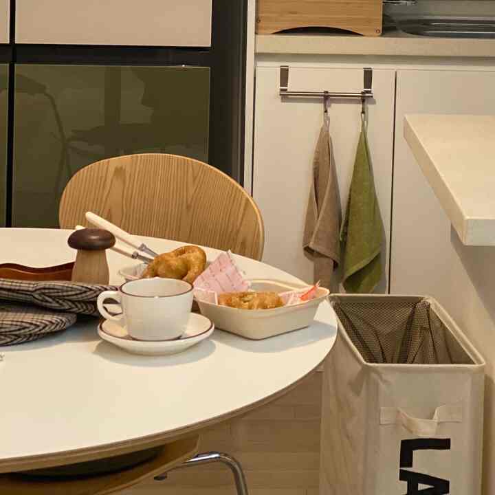 ホワイトとナチュラルカラーのキッチン、丸テーブルにコーヒーカップとプレッツェルが置かれた雰囲気のあるおうちカフェ空間