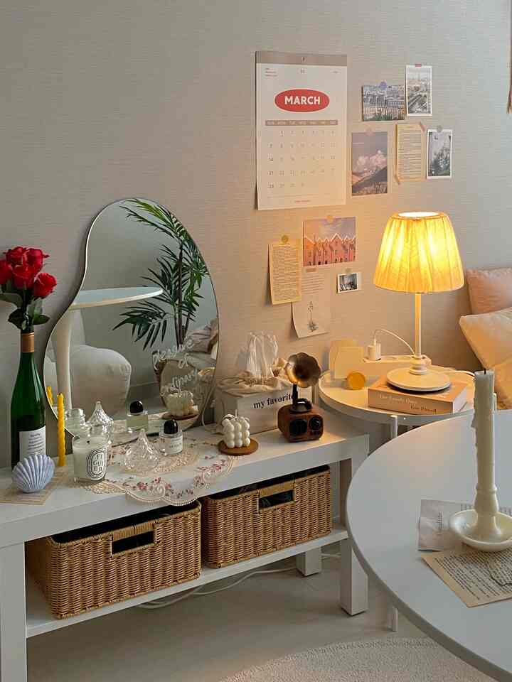 Natural modern living space in beige and white tones featuring an irregular mirror, candles, and rattan storage baskets creating a cozy atmosphere
