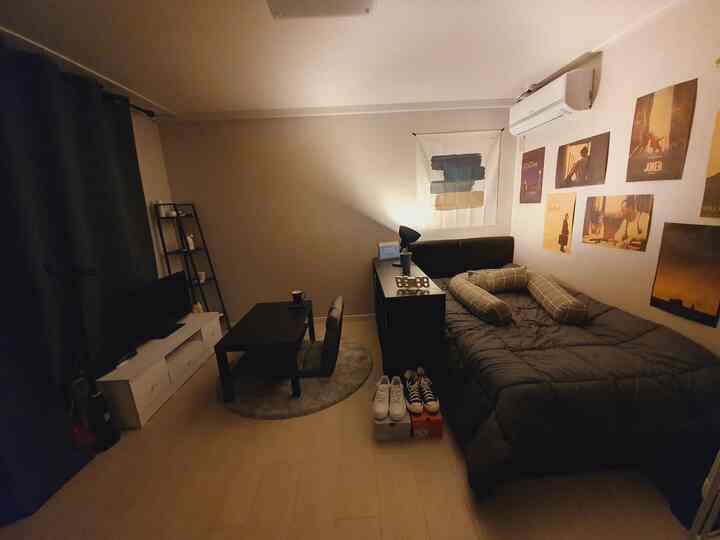 Natural toned studio bedroom featuring dark bed and coffee table in a simple, cozy space