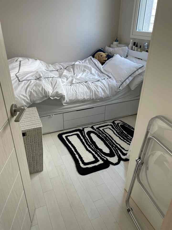 White and black toned bedroom featuring a bed with storage drawers and a plush dog toy creating a cozy atmosphere
