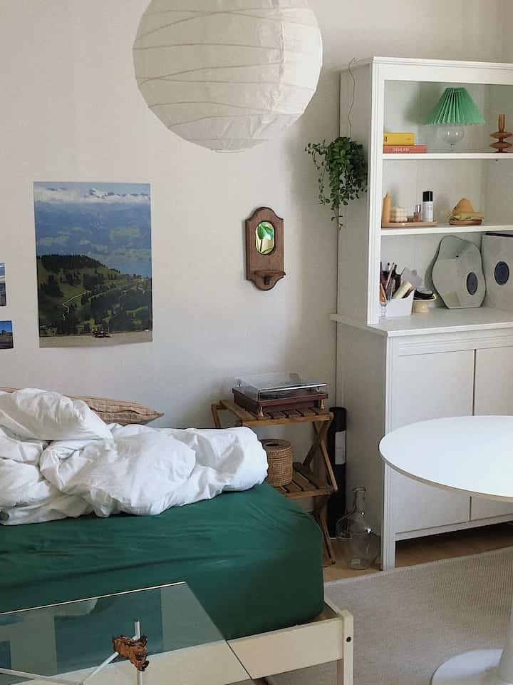 White and natural color living room featuring a bed and bookshelf in a minimalistic interior