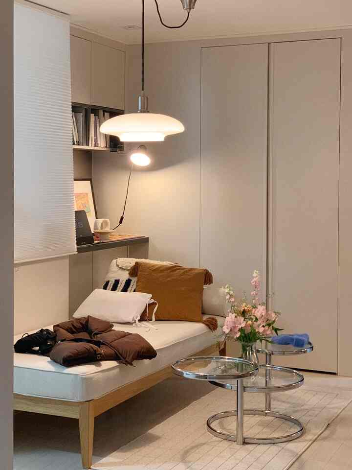 Cozy living room featuring white and natural wood tones, with a daybed sofa and vase creating a relaxed atmosphere