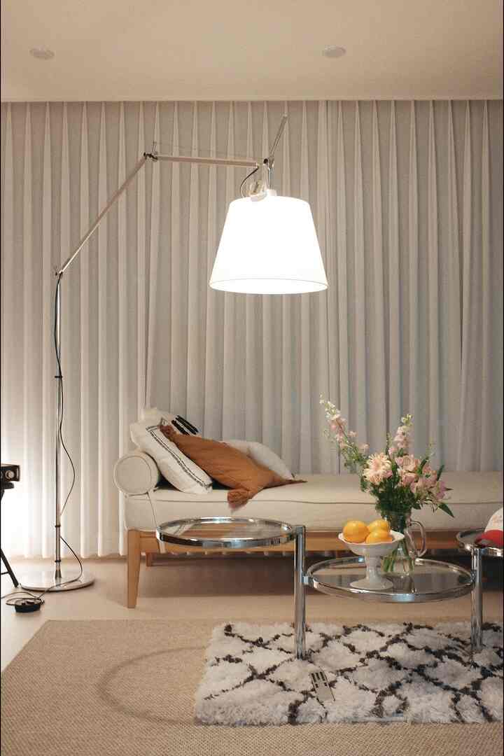 Beige and white toned living room featuring a daybed, round metal frame tables, and a floor lamp creating a cozy atmosphere
