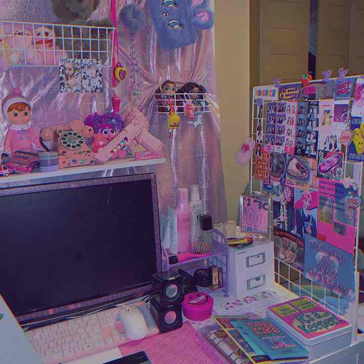 ピンク色調のデスクトップとモニター、化粧品が配置された雰囲気のある在宅勤務用ホームオフィス