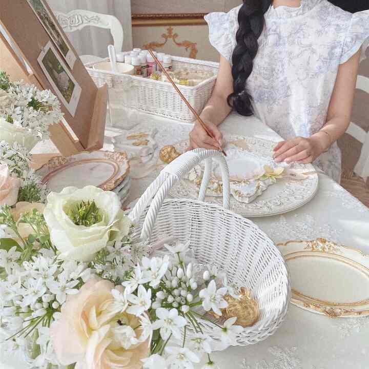 White and beige toned table featuring antique-style plaster trays and flowers in a classic atelier workspace atmosphere