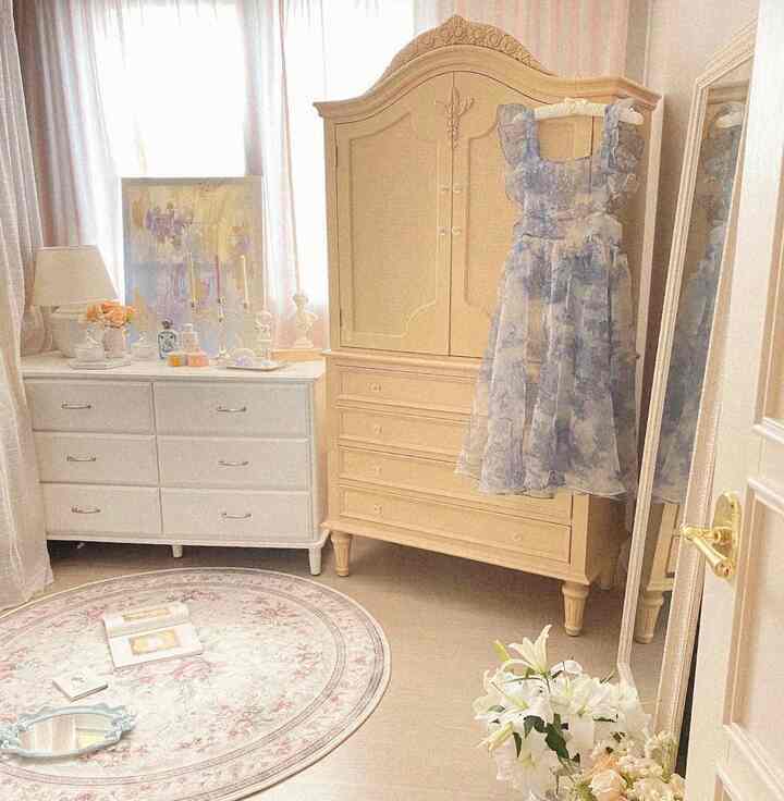 Beige and white toned walk-in closet featuring a classic armoire and white dresser, creating a soft atmosphere