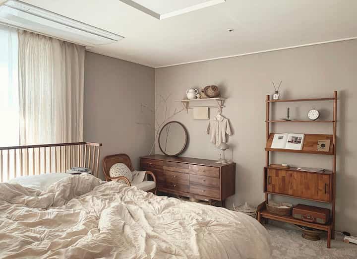 Natural bedroom in beige and wood tones featuring wooden furniture and a round mirror with a cozy and comfortable atmosphere