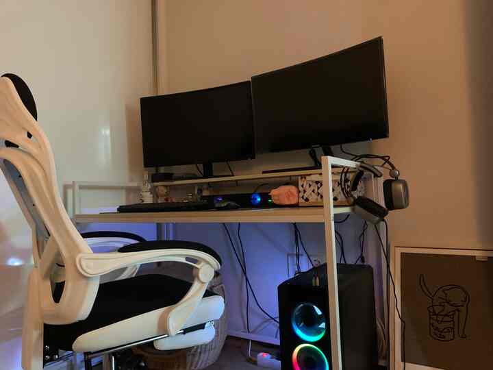 White and black toned home office featuring dual monitors and office chair in a modern workspace