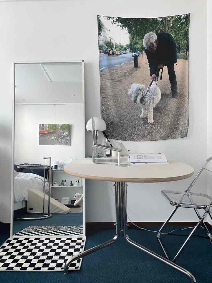 白と青の落ち着いた色調のワンルームリビング、 大きな全身鏡、透明の椅子、丸いテーブルが配置されたモダンですっきりとした印象のインテリア