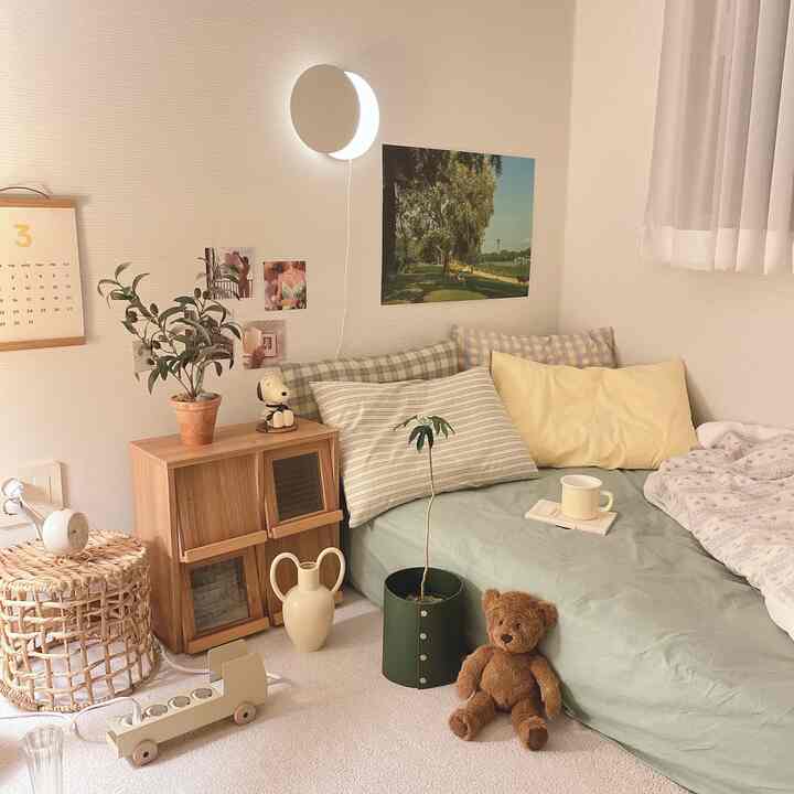 Cozy bedroom with white walls and wood tones, featuring pillow covers, a poster, and a teddy bear creating a natural ambiance