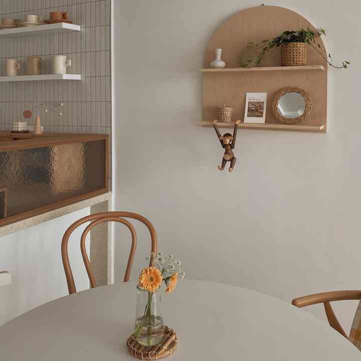 ベージュのナチュラルトーンが特徴のダイニング、木製棚と椅子が配された雰囲気のあるインテリア