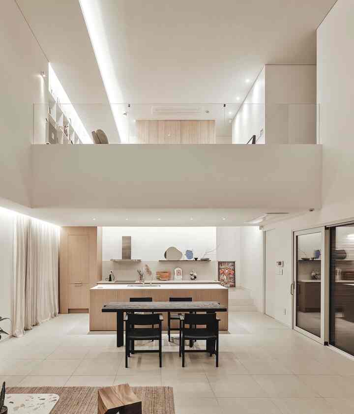 Natural color and white toned open kitchen and dining table in a modern styled space featuring a loft area