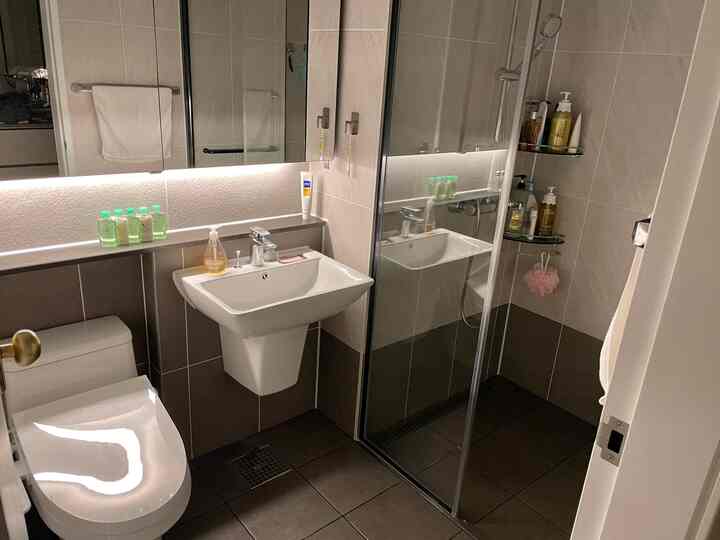 White and gray toned couple bathroom featuring shower booth and indirect lighting in a clean space