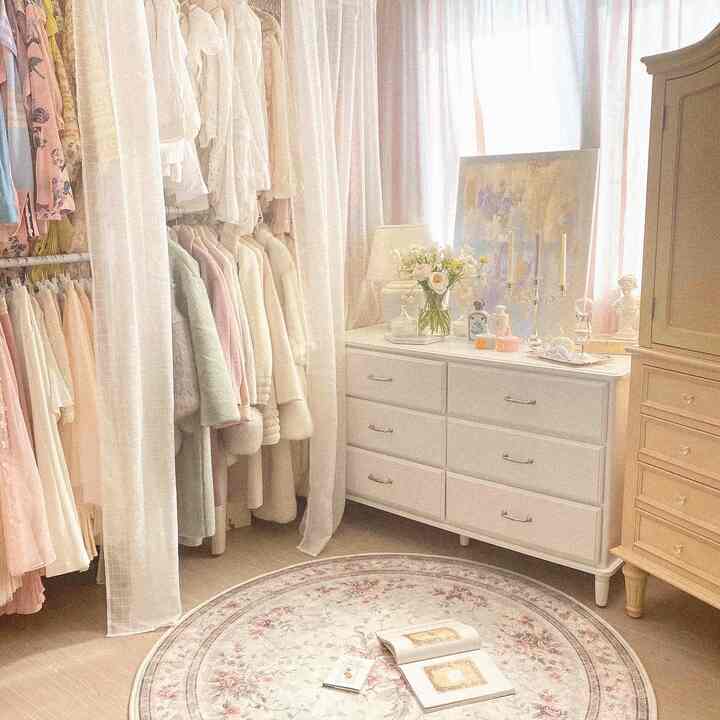 A white and pastel-toned walk-in closet featuring a white dresser and floral round carpet, creating a cozy atmosphere