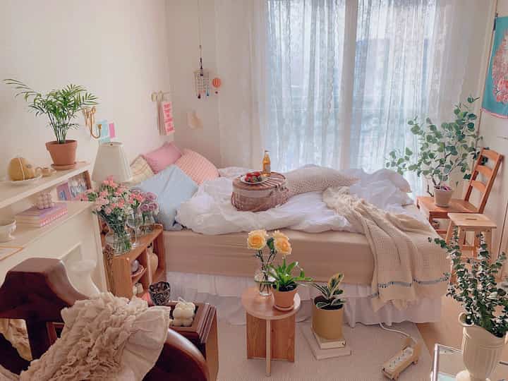 White and wood tone bedroom featuring multiple plants and flowers creating a natural, cozy atmosphere