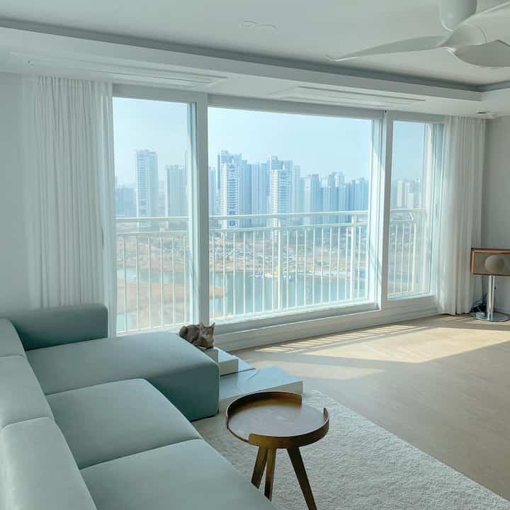 白とナチュラルカラーのモダンなリビング、広い窓から明るい自然光が差し込む雰囲気のあるインテリア