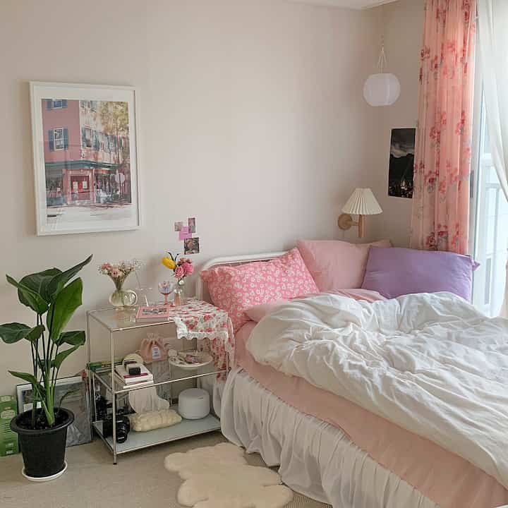 ピンクと白のトーンが調和した寝室、花瓶と植物が配置された暖かく明るいインテリア