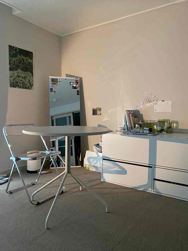 White and transparent toned small round room featuring a round dining table and transparent folding chair, showcasing a simple style