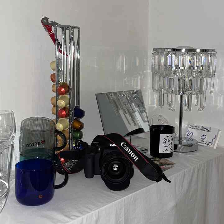 White tablecloth featuring cups, a mirror, camera, and crystal lighting in a neat home cafe setup