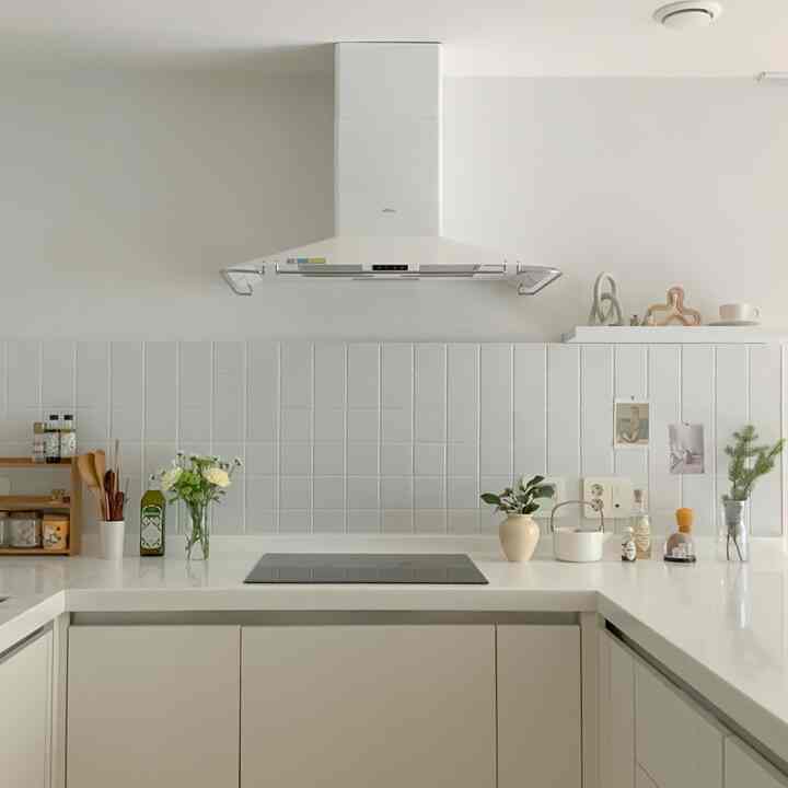Bright and clean white-toned kitchen featuring induction cooktop, multiple vases, and decorative objects with natural and simple style