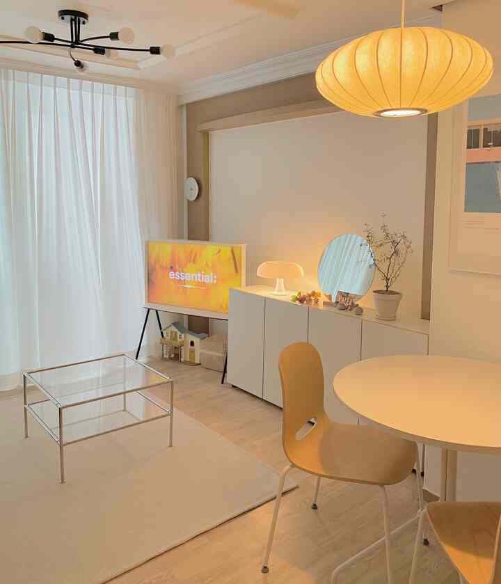 White and wood tone living room featuring a round table and desk storage cabinet, presenting a simple and natural modern space