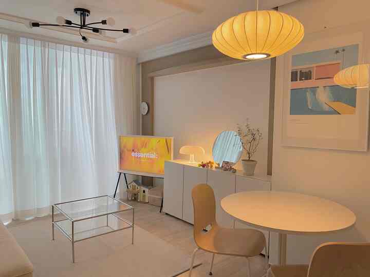 Bright and warm white and wood tone living room featuring a round table and storage cabinet in a simple modern interior
