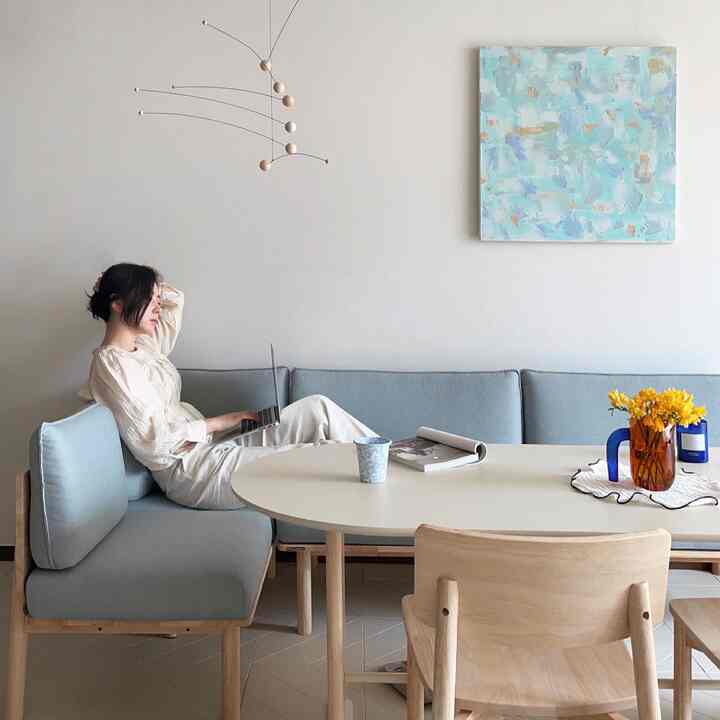 Bright light blue and white toned living room featuring natural wood dining table, fabric sofa, creating a modern and cozy interior