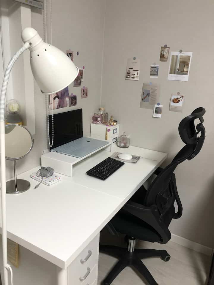 Monotone white small home office featuring a clean white desk and black office chair in a compact workspace