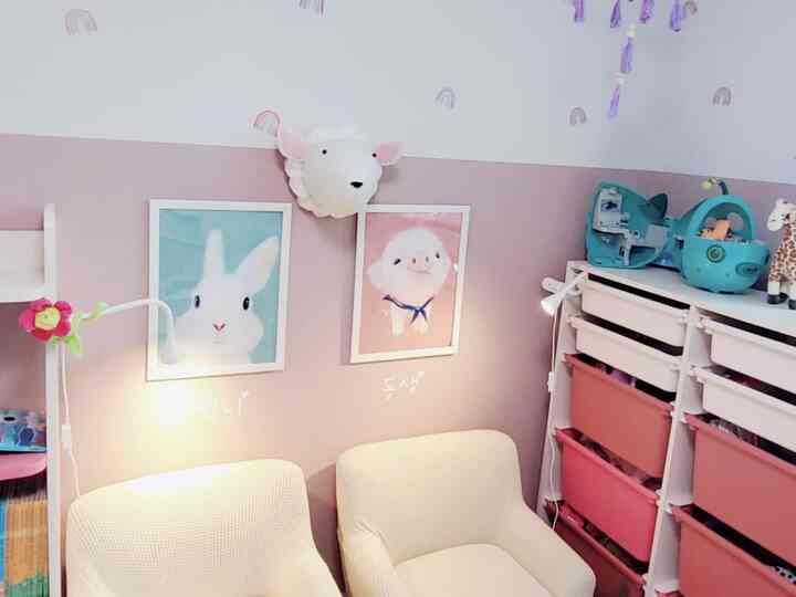 Pink and white toned kids' room featuring cute character picture frames and organized storage creating a cozy atmosphere