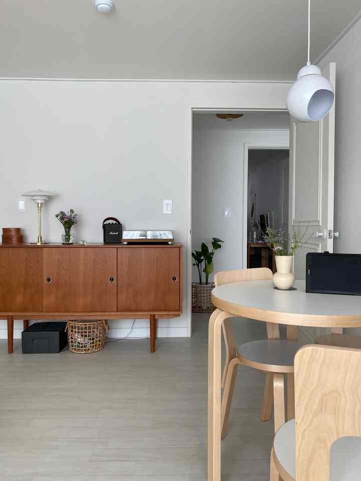 A natural modern living room with white walls and brown sideboard, featuring a round dining table and chairs creating a cozy atmosphere
