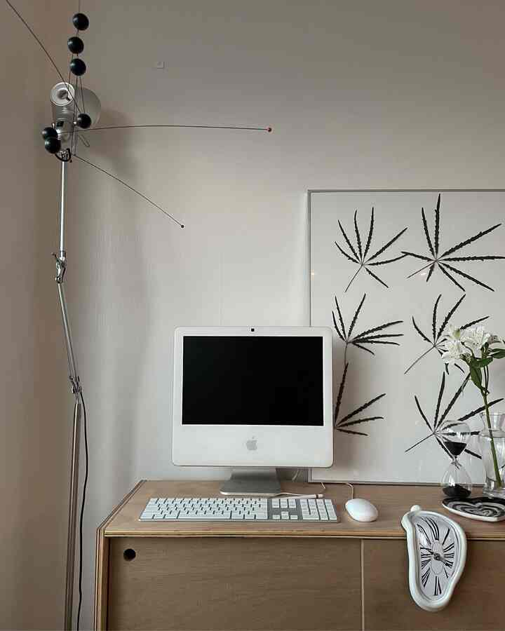 ナチュラルカラーとシルバーのトーンが調和したモダンなホームオフィス、コンピューターと額縁アートが置かれた空間