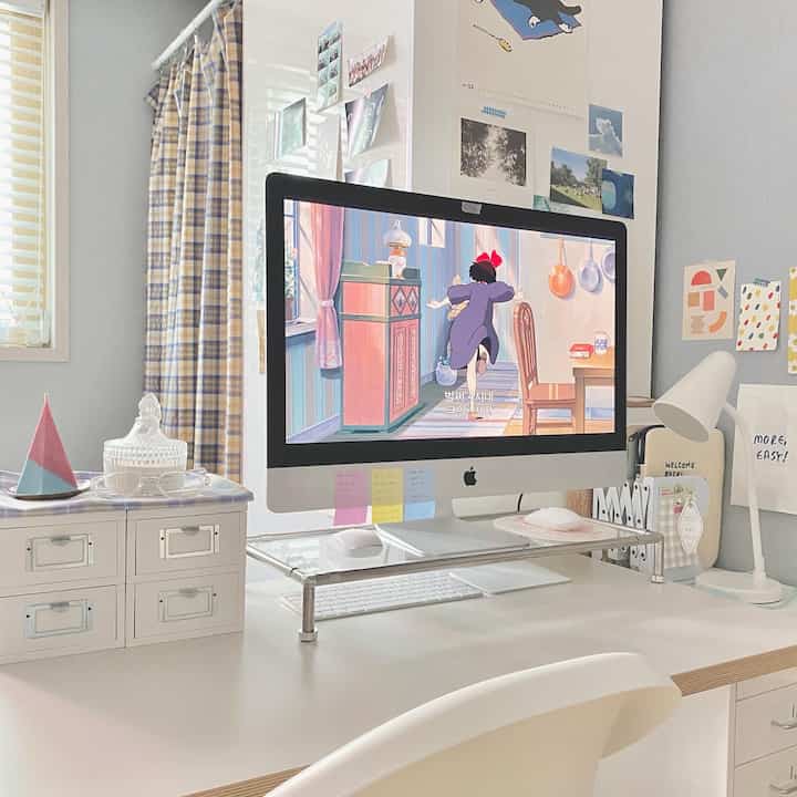 White and blue toned compact study room featuring a desk with an iMac, desk lamp, and neatly arranged stationery items