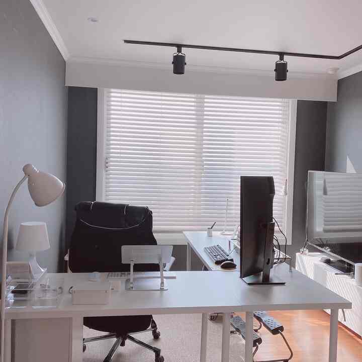白と黒のミニマリストなコンピュータールーム、白いデスクとブラインドが配置された清潔感のあるホームオフィスの空間