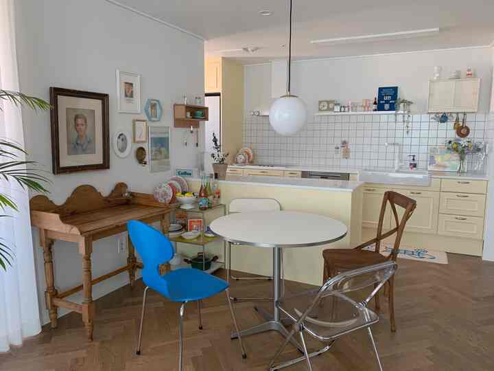 White and beige toned kitchen and dining room featuring vintage wooden furniture and picture frames with a natural warm atmosphere