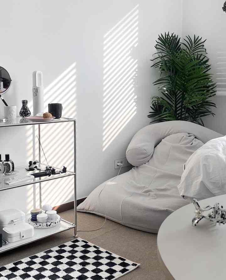 White and beige toned living room featuring a beige bean bag and green plant, offering a calm and natural atmosphere