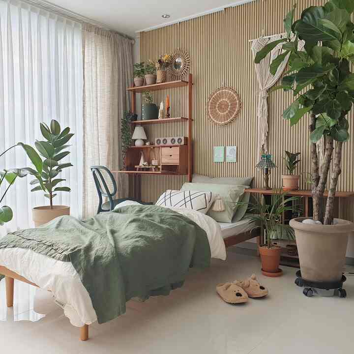 ナチュラルな木目調と緑が調和したワンルーム空間、ベッドやデスク、多様な観葉植物が配置された雰囲気のあるインテリア